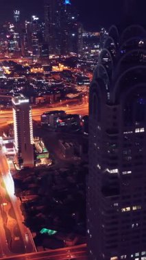 İkonik gökdelenlerin gece görüşü ve Dubai, BAE 'deki büyük bir kavşakta yoğun trafik. Modern bir şehrin çarpıcı silueti iş, finans ve kentsel gelişimi sembolize ediyor..