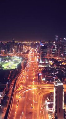 İkonik gökdelenlerin gece görüşü ve Dubai, BAE 'deki büyük bir kavşakta yoğun trafik. Modern bir şehrin çarpıcı silueti iş, finans ve kentsel gelişimi sembolize ediyor..