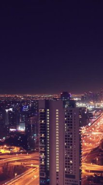 İkonik gökdelenlerin gece görüşü ve Dubai, BAE 'deki büyük bir kavşakta yoğun trafik. Modern bir şehrin çarpıcı silueti iş, finans ve kentsel gelişimi sembolize ediyor..
