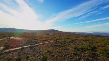 Gün batımında virajlı dağ yolunda bisikletçi. Etrafı canlı sonbahar yapraklarıyla çevrili. Seyahat macerası için ideal doğa ve mevsimsel yaşam tarzı temaları.
