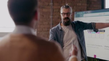 Moden ofis alanı, iş dünyasından profesyonellerden oluşan bir ekip canlı tartışmalara girişiyor ve stratejik fikirleri paylaşıyor, modern kurumsal açık alanların merkezinde işbirliği ve yenilik sergiliyor.