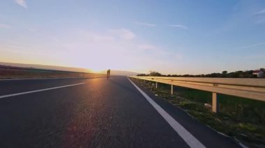 Dağ yolunda kadın bisikletçi gün batımında canlı sonbahar yeşillikleriyle çevrili. Gezgin maceralar için ideal doğa ve mevsimsel yaşam tarzı temaları.