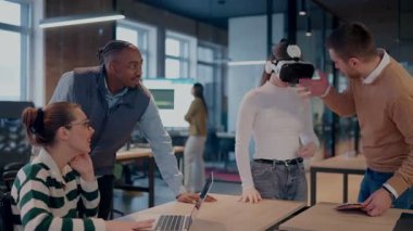 Modern bir iş yerinde çalışan tekerlekli sandalyedeki engelli bir iş kadını. Çevredeki ekip sanal gerçeklik gözlükleri kullanıyor, açık alan yaratıcılığında en son teknolojiyle işbirliği yapıyorlar.