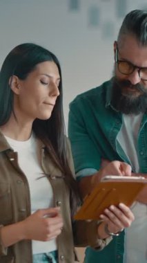 Yaratıcı milenyumlar, sıradan iş adamları, küçük işletme sahipleri, sosyal medya stratejisi ve marka geliştirme üzerinde çalışan modern, açık bir ofis ortamında dijital tabletle