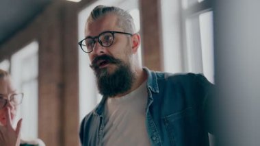 Moden ofis alanı, iş dünyasından profesyonellerden oluşan bir ekip canlı tartışmalara girişiyor ve stratejik fikirleri paylaşıyor, modern kurumsal açık alanların merkezinde işbirliği ve yenilik sergiliyor.