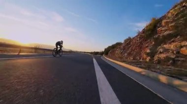 Dağ yolunda kadın bisikletçi gün batımında canlı sonbahar yeşillikleriyle çevrili. Gezgin maceralar için ideal doğa ve mevsimsel yaşam tarzı temaları.