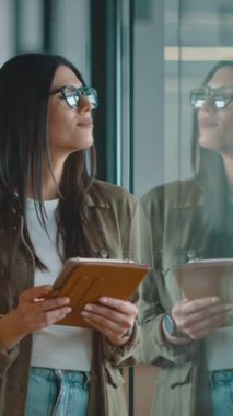 Kendine güveni tam bir iş kadını ve modern bir açık alan çalışma ofisinde dijital tablet tutan şık giyimli bir şirket yöneticisi. Profesyonel kadın çalışan Fintech teknolojisini kullanıyor.