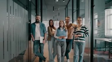 Modern bir ortak çalışma ofisindeki çeşitli profesyonellerden oluşan bir ekip, birlikte gülümsüyor, takım çalışması, işbirliği ve yenilikleri destekleyen pozitif bir şirket kültürü ve dinamik bir çalışma sergiliyor.