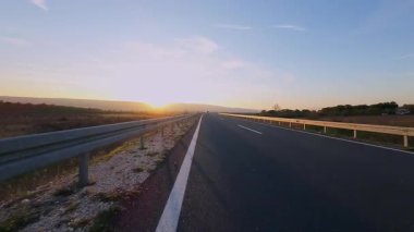 Dağ yolunda kadın bisikletçi gün batımında canlı sonbahar yeşillikleriyle çevrili. Gezgin maceralar için ideal doğa ve mevsimsel yaşam tarzı temaları.
