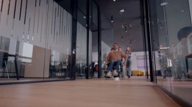Tekerlekli sandalyede engelli bir iş adamı, modern bir ofiste takım çalışmasının, dahil olmanın ve güçlenmenin gücünü ortaya koyan destekleyici meslektaşlarıyla çevrilidir.. 
