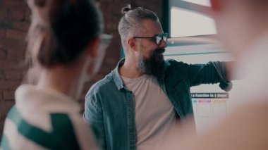 Moden ofis alanı, iş dünyasından profesyonellerden oluşan bir ekip canlı tartışmalara girişiyor ve stratejik fikirleri paylaşıyor, modern kurumsal açık alanların merkezinde işbirliği ve yenilik sergiliyor.