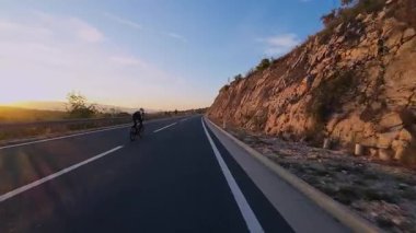 Dağ yolunda kadın bisikletçi gün batımında canlı sonbahar yeşillikleriyle çevrili. Gezgin maceralar için ideal doğa ve mevsimsel yaşam tarzı temaları.