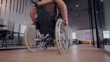 Tekerlekli sandalyede engelli bir iş adamı, modern bir ofiste takım çalışmasının, dahil olmanın ve güçlenmenin gücünü ortaya koyan destekleyici meslektaşlarıyla çevrilidir.. 