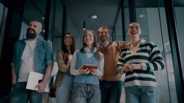 Modern bir ortak çalışma ofisindeki çeşitli profesyonellerden oluşan bir ekip, birlikte gülümsüyor, takım çalışması, işbirliği ve yenilikleri destekleyen pozitif bir şirket kültürü ve dinamik bir çalışma sergiliyor.