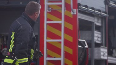 İtfaiyeci ya da itfaiyeci, istasyondaki eğitim sırasında yangın söndürme borusundan su sıkmak için antrenman yapıyor. Felaketleri önlemek için güvenlik uygulaması kavramı. Yüksek kalite 4k