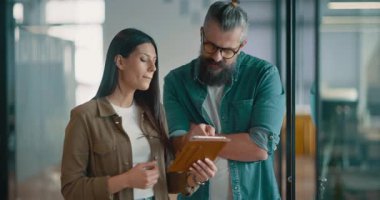 Yaratıcı milenyumlar, sıradan iş adamları, küçük işletme sahipleri, sosyal medya stratejisi ve marka geliştirme üzerinde çalışan modern, açık bir ofis ortamında dijital tabletle