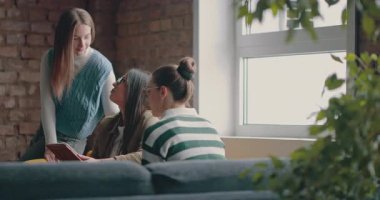 Kadın iş adamları pencere kenarında iş birliği yapıyor, fikirleri tartışıyor ve tablet üzerinde beyin fırtınası yapıyorlar. Modern bir ofiste işbirliği, yaratıcılık ve takım çalışması kavramı