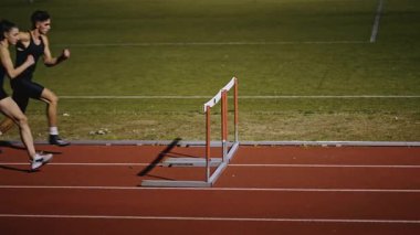 Stadyuma atletik zinde bir çift erkek ve kadın fırlatılıyor. Sıcak bir yaz öğleden sonrasında engellerin üzerinden atlamak. Yavaş Hareket İzleme Görüntüsü. 