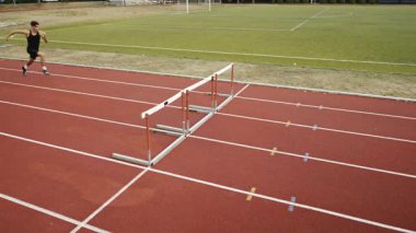 Stadyuma atletik zinde bir çift erkek ve kadın fırlatılıyor. Sıcak bir yaz öğleden sonrasında engellerin üzerinden atlamak. Yavaş Hareket İzleme Görüntüsü. 