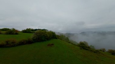 Bereketli yeşil orman dağlarının hava manzarası sisli ve alçak asılı bulutların altında kasvetli bir bulutun altında sakin ve gizemli bir doğal manzara yaratıyor..