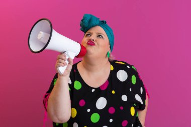 Renkli puantiyeli kıyafetli kendine güvenen bir kadın ve eski kafa örtüsü ile megafona bağırıyor, güçlü bir duygu ve tavır sergiliyor.. 