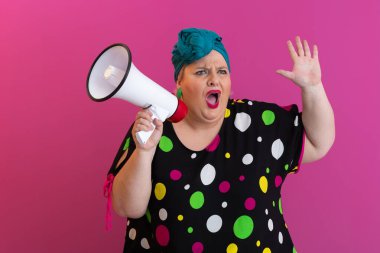 Renkli puantiyeli kıyafetli kendine güvenen bir kadın ve eski kafa örtüsü ile megafona bağırıyor, güçlü bir duygu ve tavır sergiliyor.. 