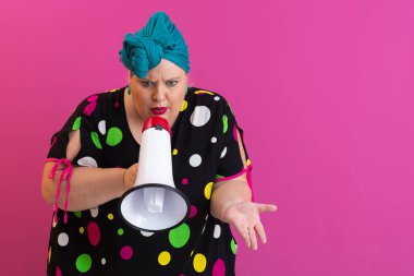 Renkli puantiyeli kıyafetli kendine güvenen bir kadın ve eski kafa örtüsü ile megafona bağırıyor, güçlü bir duygu ve tavır sergiliyor.. 