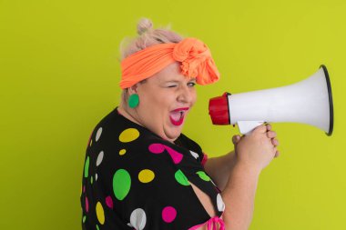 Renkli puantiyeli kıyafetli kendine güvenen bir kadın ve yeşil bir arka plana karşı güçlü duygu ve tutumunu ifade eden megafona bağıran retro başlıklı bir kadın.. 