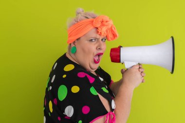 Renkli puantiyeli kıyafetli kendine güvenen bir kadın ve yeşil bir arka plana karşı güçlü duygu ve tutumunu ifade eden megafona bağıran retro başlıklı bir kadın.. 