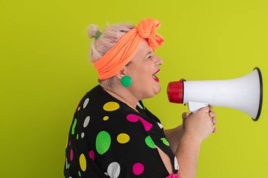 Renkli puantiyeli kıyafetli kendine güvenen bir kadın ve yeşil bir arka plana karşı güçlü duygu ve tutumunu ifade eden megafona bağıran retro başlıklı bir kadın.. 