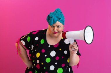 Renkli puantiyeli kıyafetli kendine güvenen bir kadın ve eski kafa örtüsü ile megafona bağırıyor, güçlü bir duygu ve tavır sergiliyor.. 