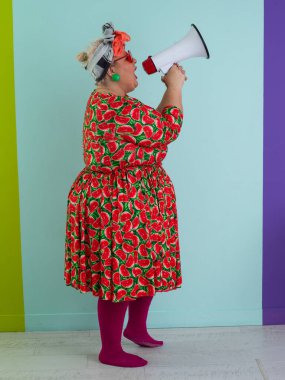 Renkli puantiyeli kıyafetli kendine güvenen bir kadın ve retro başlıklı bir kadın megafona bağırıyor, mavi bir arka plana karşı güçlü bir duygu ve tavır sergiliyor.. 