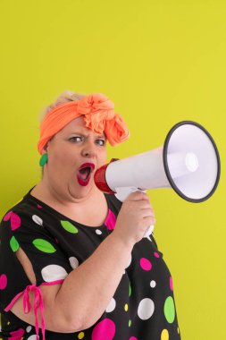 Renkli puantiyeli kıyafetli kendine güvenen bir kadın ve yeşil bir arka plana karşı güçlü duygu ve tutumunu ifade eden megafona bağıran retro başlıklı bir kadın.. 