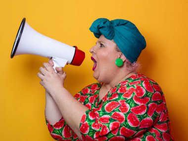Renkli puantiyeli kıyafetli kendine güvenen bir kadın ve sarı bir arka plana karşı güçlü duygu ve tutumunu ifade eden megafona bağıran retro başlıklı bir kadın.. 