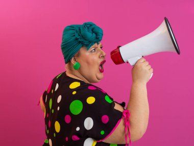 Renkli puantiyeli kıyafetli kendine güvenen bir kadın ve eski kafa örtüsü ile megafona bağırıyor, güçlü bir duygu ve tavır sergiliyor.. 