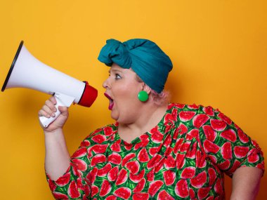 Renkli puantiyeli kıyafetli kendine güvenen bir kadın ve sarı bir arka plana karşı güçlü duygu ve tutumunu ifade eden megafona bağıran retro başlıklı bir kadın.. 