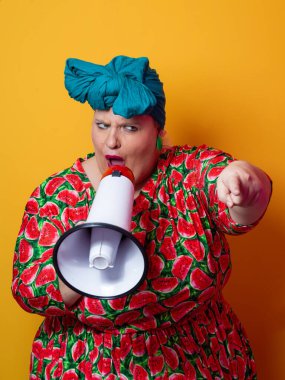Renkli puantiyeli kıyafetli kendine güvenen bir kadın ve sarı bir arka plana karşı güçlü duygu ve tutumunu ifade eden megafona bağıran retro başlıklı bir kadın.. 