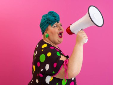 Renkli puantiyeli kıyafetli kendine güvenen bir kadın ve eski kafa örtüsü ile megafona bağırıyor, güçlü bir duygu ve tavır sergiliyor.. 