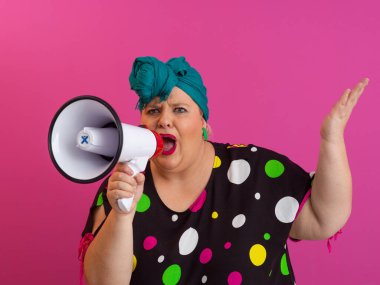 Renkli puantiyeli kıyafetli kendine güvenen bir kadın ve eski kafa örtüsü ile megafona bağırıyor, güçlü bir duygu ve tavır sergiliyor.. 