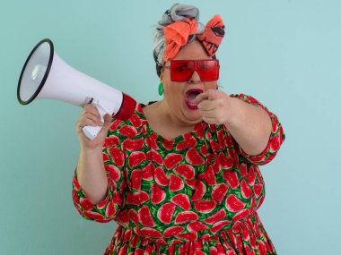 Renkli puantiyeli kıyafetli kendine güvenen bir kadın ve retro başlıklı bir kadın megafona bağırıyor, mavi bir arka plana karşı güçlü bir duygu ve tavır sergiliyor.. 