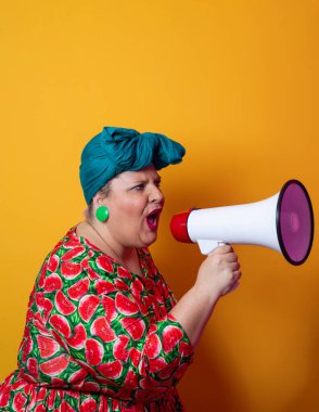 Renkli puantiyeli kıyafetli kendine güvenen bir kadın ve sarı bir arka plana karşı güçlü duygu ve tutumunu ifade eden megafona bağıran retro başlıklı bir kadın.. 