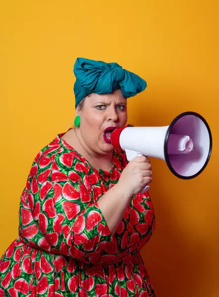 Renkli puantiyeli kıyafetli kendine güvenen bir kadın ve sarı bir arka plana karşı güçlü duygu ve tutumunu ifade eden megafona bağıran retro başlıklı bir kadın.. 