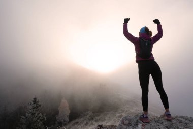 Kadın adam gün batımında bir dağın tepesinde duruyor. Hedefler ve başarılar konsept fotoğraf birleşimi. Kavramsal görüş, yürüyüş ya da patika koşucusu dağlara bakar ve güneşin doğuşunun tadını çıkarır..