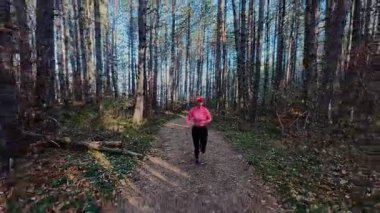 Dağlardaki bir sonbahar ormanında koşan dişi bir koşucunun gizli bir fotoğrafı. Sabah sporları aktif yaşam tarzı, uygunluk, dayanıklılık ve doğa odaklı eğitim maratonunu gözler önüne seriyor