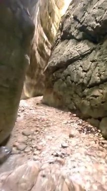 Dik, yıpranmış uçurum duvarlarıyla çevrili sığ bir akıntıyla dar kayalık kanyon dramatik, güneşli bir manzarada doğal erozyon ve macera yakalıyor. Dikey hava fpv