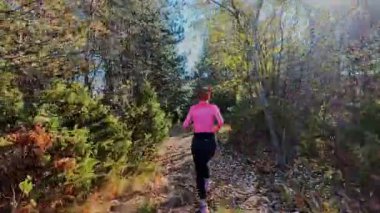 Dağlardaki bir sonbahar ormanında koşan dişi bir koşucunun gizli bir fotoğrafı. Sabah sporları aktif yaşam tarzı, uygunluk, dayanıklılık ve doğa odaklı eğitim maratonunu gözler önüne seriyor