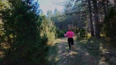 Dağlardaki bir sonbahar ormanında koşan dişi bir koşucunun gizli bir fotoğrafı. Sabah sporları aktif yaşam tarzı, uygunluk, dayanıklılık ve doğa odaklı eğitim maratonunu gözler önüne seriyor