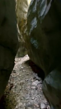 Dik, yıpranmış uçurum duvarlarıyla çevrili sığ bir akıntıyla dar kayalık kanyon dramatik, güneşli bir manzarada doğal erozyon ve macera yakalıyor. Dikey hava fpv