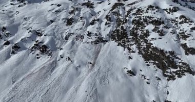 Karla kaplı dağların, güneşli gökyüzünün ve kayak, snowboard, yürüyüş ve açık hava maceraları için mükemmel manzaralı yamaçların nefes kesici hava manzarası.
