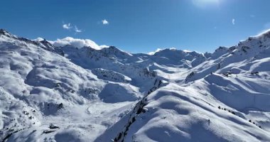 Karla kaplı dağların, güneşli gökyüzünün ve kayak, snowboard, yürüyüş ve açık hava maceraları için mükemmel manzaralı yamaçların nefes kesici hava manzarası.